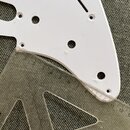 Bílá pickguard pro kytaru s několika otvory a jedním úzkým podélným výřezem. Kolem některých otvorů jsou vidět drobné stopy opotřebení nebo znečištěn…