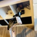 Detail hlavy elektrické kytary s bílým povrchem a červenými žilkami připomínajícími mramor. Na hraně hlavy je viditelné opotřebení a odloupaná barva.…
