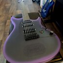 Fialová elektrická kytara s matným povrchem a černým pickguardem. Nástroj má dva humbuckery, jeden ovládací knoflík a přepínač. Na těle je v dolní čá…