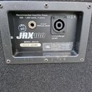 Detail zadní strany reproduktoru s černým povrchem. Na štítku jsou nápisy „Recommended Amplifier Power 500 - 1,000 watts, 4 ohms“, „IN / OUT (PARALLE…