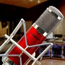 Červený kondenzátorový mikrofon s kovovou síťkovou hlavou v chromovaném šockmountu. Na těle mikrofonu je oválné logo s nápisem AVANTONE a v dolní čás…