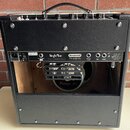 Zadní strana kytarového komba v černém koženěném potahu s otevřeným zadním panelem. Na ovládacím panelu jsou nápisy SingleMan, Brunetti Tube amplific…