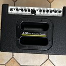 Černý kytarový kombo zesilovač s texturovaným povrchem. Na přední straně je žlutý nápis AER The Acoustic People a v horní ovládací části text Compact…