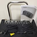 Černý keyboardový zesilovač s nápisem Peavey KB5. Na horním ovládacím panelu jsou čtyři kanály s knoflíky a přepínači. Na přístroji leží černý napáje…