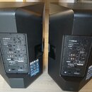Dvě černé aktivní reproduktory značky YAMAHA, model DXR15. Na zadním panelu jsou viditelné ovládací prvky, konektory a nápisy včetně označení DXR15 P…