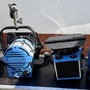 Čtyři modré studiové reflektory značky ARRI s bílými chladiči a černými držáky. Na každém z přístrojů je viditelný nápis ARRI a označení T1. Reflekto…