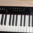 Černý digitální klavír s bílými a černými klávesami. Na ovládacím panelu jsou nápisy TEMPO, SOUND MODE, REC, TONE, PIANO, E.PIANO, ORGAN, STRINGS, PA…