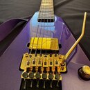 Fialová elektrická kytara s kovovými komponenty v zlatém provedení. Na kobylci je viditelný nápis Floyd Rose. Kytara má jeden zlatý humbucker, zlatý…
