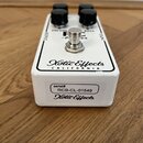 Bílý kytarový efekt s nápisem Xotic Effects CALIFORNIA. Na horní straně jsou čtyři černé otočné knoflíky a stoupací spínáč, vedle kterých jsou nápisy…