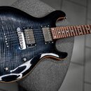Tmavě modrá elektrická kytara s výraznou strukturou dřeva na topu. Nástroj má dva humbuckery, Tune-o-matic most a tři ovládací knoflíky. Na hlavě kyt…