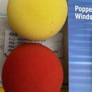 Dvě kulovité pěnové clony na mikrofon v žluté a červené barvě. Vedle nich je vidět část modré krabice s bílým nápisem A58WS-YEL YELLOW a Poppe Winds.…