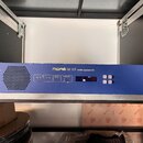 Modré rackové zařízení s nápisem MIDAS DL151 audio system I/O. Na předním panelu jsou umístěny kontrolky, displej a tlačítka s nápisy menu, select a…