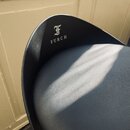 Detail černé židle s koženým nebo syntetickým potahem. Na zadní části opěradla je bílý nápis FURCH a nad ním stylizované písmeno F. Povrch materiálu…