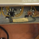 Detailní pohled do vnitřku elektroniky přístroje. Jsou vidět dva potenciometry s připojenými žlutými vodiči a jeden přepínač. Na spodní kovové části…