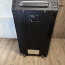 Černý basový kombo zesilovač v transportním case s kovovou rukojetí a kolečky. Na přední straně je nápis GALLIEN KRUEGER a ovládací panel s knoflíky…