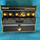 Černý kompresor s žlutými detaily a ovládacími knoflíky. Na horní části je nápis Markbass a COMPRESSORE. Pod knoflíky jsou popisky GAIN, THRESHOLD, R…