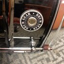Detail chromovaného povrchu bubnu s kulatým černobílým logem. Na logu je doslovně napsáno DRUM GEAR TACTICAL GEAR FOR DRUMMERS. Pod logem je vidět čá…