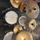 Kompletní bicí souprava s několika činely. Na bubnech jsou viditelné nápisy EVANS a TAMA, na činelech značka Zildjian s označením CUSTOM a písmeno K.…