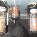 Tři elektronické vacuumové lampy v držácích. Na sklech a horních bílých štítcích jsou oranžová loga s písmenem G v kruhu a nápisy FBO, Premium a GT-6…