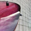 Detail zadní strany kytary s fialovo-červeným lakem a viditelnou strukturou dřeva. Na povrchu je umístěn černý oválný knofík a na hraně těla vyčnívá…
