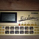 Zlatý rytmický programátor značky YAMAHA s nápisem Big Jam RY9 RHYTHM PROGRAMMER. Zařízení má LCD displej a řadu ovládacích tlačítek s označením jedn…