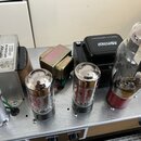Vnitřek elektronického zařízení s kovovým šasi. Jsou zde vidět tři elektronky, dva transformátory a jeden černý blok s nápisem Mercury. Na jednom z t…