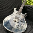 Elektrická kytara s modře žilkovaným povrchem těla a hnedým hřidlem. Na hmatníku je viditelné logo PRS. Kytara má dva humbuckery, pěticestný přepínač…