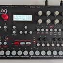 Černý analogový syntetizátor značky Elektron s nápisem „analog FOUR 4 Voice Analog Synthesizer“. Přístroj má v horní části displej, několik otočných…