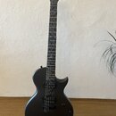 Černá elektrická kytara s matným povrchem a černým hmatníkem. Na hlavě je bílý nápis enya. Kytara má dva humbuckery, jeden ovládací knoflík a přepína…