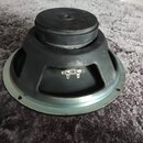 Fotografie zachycuje zadní stranu reproduktoru s černým magnetem a kovovým rámem. Na spodní části rámu jsou vidět dva kovové kontakty pro připojení k…