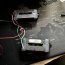 Dvě elektrické kytarové snímače typu humbucker s černým plastovým krytem a viditelnými póly. Na spodní straně jednoho ze snímačů je bílá nálepka s ná…