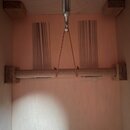 Detail vnitřku dřevěného kufru nebo pouzdra. Uvnitř je umístěna vodorovná dřevěná tyč s připojeným šňůrkou. Na vnitřní stěně jsou vidět dvě svislé ob…