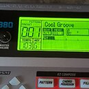 Černý rytmický doprovod Boss Dr.Rhythm DR-880 s podsvíceným LCD displejem, na kterém je text Cool Groove a hodnoty 001, 4/4, 001-1, G7 a tempo 103. Z…