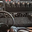 Záběr na zadní panel černého elektronického zařízení. Je zde vidět nápis YAMAHA a MODEL NY84-D, dále loga Dante a označení PRIMARY, SECONDARY, FOOT S…