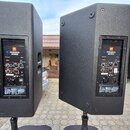 Dvě černé aktivní reproduktory umístěné na stojanech. Na zadním panelu obou kusů je vidět logo JBL a nápis PRX800 SERIES. Povrch je z černého texturo…