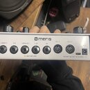 Bílý efektový pedál značky meris. Na zadní straně jsou konektory s nápisy L [MONO] IN, R IN, L [MONO] OUT, R OUT, EXP, MIDI IN a MIDI OUT, dále vstup…