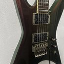 Elektrická kytara s tmavě hnědým kovovými lakem a hranatým tvarem těla. Nástroj má dva humbuckery, tremolo systém a dvě ovládací knoflíky. Na těle ne…