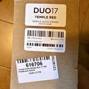 Kartonová krabice s třemi bílými nálepkami. První nálepka obsahuje text DUO17, TEMPLE RED, TEMPLE AUDIO DESIGN a MADE IN CANADA. Druhá nálepka obsahu…