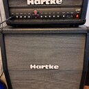 Kytarové kombo typu stack značky Hartke. Horní část tvoří zesilovač s ovládacími prvky, kde jsou viditelné nápisy INPUT, CRUNCH, VOLUME, BASS, TREBLE…