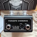 Černý kytarový efekt s nápisem PARASITE OVERDRIDE a označením CT-PS-26A. Na spodní části je logo COLORTONE a webová adresa www.colortonepedals.com. Z…