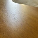 Detailní záběr na hnědý lakovaný povrch dřevěného nástroje s viditelnou strukturou zrna. V horní části jsou patrné povrchové škrábance a oděrky laku.…