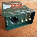 Zelená pasivní DI box s kovovým šasi. Na horní straně je červeno-bílé logo Radial Engineering a nápis PASSIVE DIRECT BOX. Na zadní straně jsou přepín…