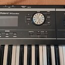 Černý digitální klavír s bílými a černými klávesami. Na ovládacím panelu je nápis Roland V-Combo, displej a ovládací prvky s označením VALUE, MENU, E…