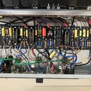 Fotografie zachycuje vnitřek elektronického zařízení s otevřeným šasi. Je viditelná černá základní deska osazená různými komponenty, jako jsou rezist…