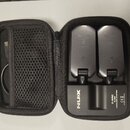 Černý přepravní pouzdro s dvěma bezdrátovými vysílači vloženími. Na spodní části pouzdra je bílý nápis NUX a text C-SRC 5.8G WIRELESS SYSTEM, CE, MAD…