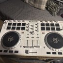 Bílý DJ 컨트롤러 s nápisem Numark MIXTRACK PRO II. Zařízení obsahuje dva jog-wheels, několik čtvercových podsvícených tlačítek a posuvníky. Povrch je v d…