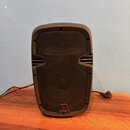 Hnědý reproduktor s kovovou mřížkou. V dolní části je umístěno logo a nápis behringer. Nástroj je připojen k elektrickému kabelu s viditelnou zástrčk…