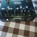 Tmavě zelený kytarový efekt s pětí knoflíky a dvěma bílými přepínači. Na horní straně je logo MXR a nápis carbon copy. V dolní části jsou tři konekto…