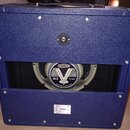 Modrá kytarová reprobox s texturovaným povrchem. Uprostřed je viditelný reproduktor značky CELESTION s nápisy V, G12 a 70-watt TYPE. Ve spodní části…
