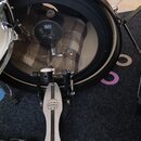 Fotografie zachycuje část bílé bicí sady. Na basovém bubnu je vidět vnitřní prostor a mikrofon značky s nápisem SENNHEISER. V popředí je umístěn pedá…